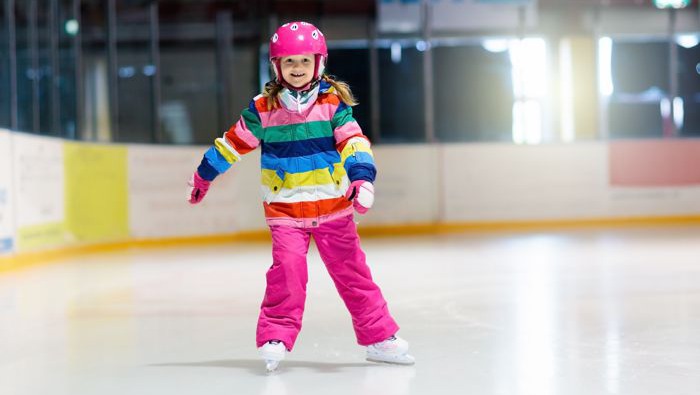Child skating on indoor ice rink. Kids skate. Active family sport during winter vacation and cold season. Little girl in colorful wear training or learning ice skating. School sport activity and clubs