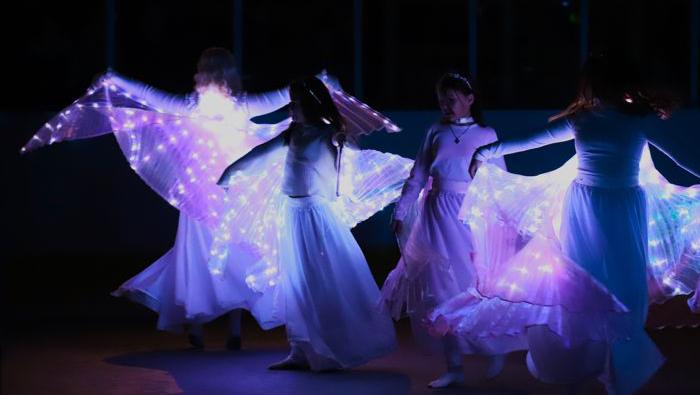 Kerstins dans uppträdde tillsammans med barn i lysande led-vingar i mörkret