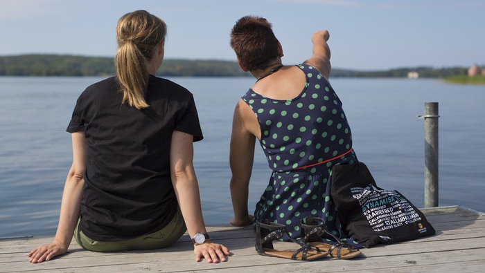 Två personer som sitter på en brygga och tittar mot vattnet