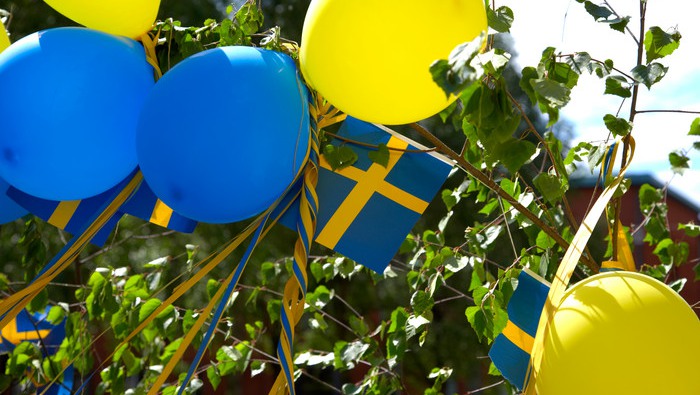 Blåa och gula ballonger med sverigeflaggor inför studentfirande.