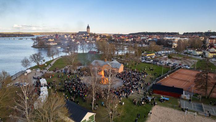 Drönarbild över Visholmen i Strängnäs. Många människor står samlade runt en valborgseld