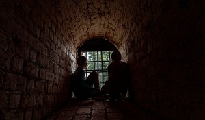 Två barn som sitter i ett mörkt slottsvalv.