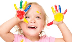 Portrait of a cute little girl showing her hands painted in bright colors, isolated over white