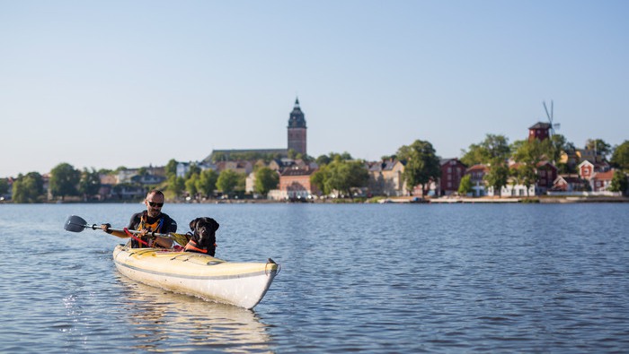 Man och hund i kajak på Mälaren med Strängnäs kyrka och kvarnen i bakgrunden