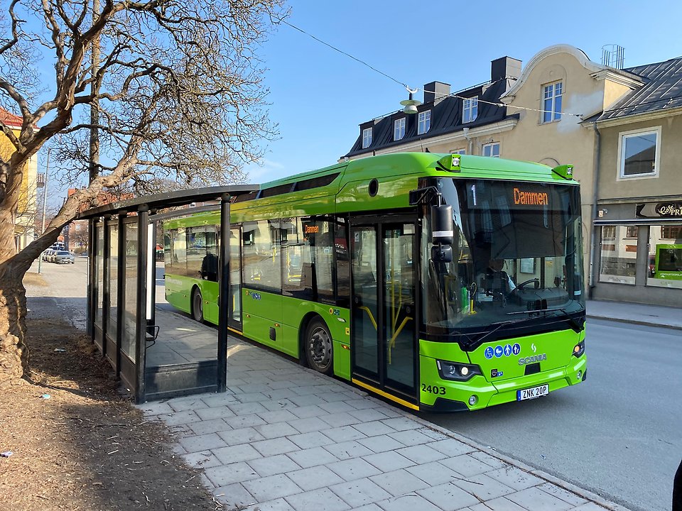 Grön buss vid hållplats i stadsmiljö